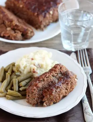 Steak Lovers' Meatloaf - A1 steak sauce, garlic, and onions on the inside, with more steak sauce slathered on the outside, makes this meatloaf both moist and delicious! From DessertNowDinnerLater.com