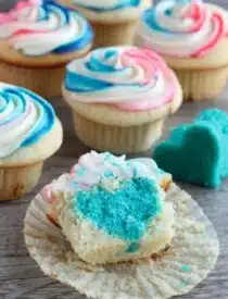 These Gender Reveal Cupcakes have pink, blue, and white swirled frosting on top that hides the secret colored heart in the center of the cupcake revealing the baby's gender when you bite into it! (Step-by-Step Photo Tutorial)