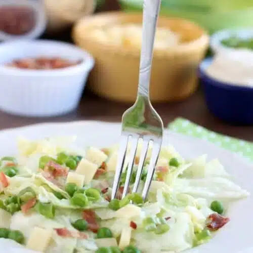 Sarah's Salad from Utah's Lion House restaurant uses crisp iceberg lettuce, peas, bacon, green onions, and swiss cheese tossed in a simple, sweet dressing.