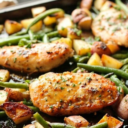 This one pan chicken dinner has the most delicious honey garlic glazed chicken alongside tenderly roasted potatoes and green beans. Plus, it's so easy and flavorful, you'll make again and again!