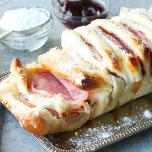 This Monte Cristo Pull Apart Bread is full of savory meats and melty cheese. It's topped with a dusting of powdered sugar and served with raspberry preserves. Works great as a breakfast, lunch, dinner, or appetizer!