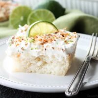 Coconut Lime Poke Cake - a fluffy, white, lime-infused cake that is soaked with coconut cream, and topped with sweetened whipped cream, toasted coconut, and lime zest. It's super moist and full of tropical flavors!