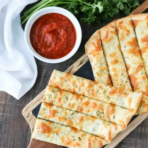 These easy Cheesy Garlic Breadsticks are loaded with garlic, cheese, and herbs for a great tasting breadstick to enjoy for pizza night. Also delicious dipped in marinara sauce!