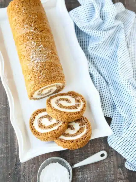 This classic Pumpkin Roll is a simple spiced pumpkin cake rolled up with the BEST cream cheese frosting inside. Use parchment paper for easy rolling -- no towel needed.