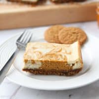 Pumpkin Swirl Cheesecake Bars have a buttery gingersnap crust, with ribbons of creamy vanilla and spiced pumpkin cheesecake marbled on top. A delicious dessert for fall or Thanksgiving.