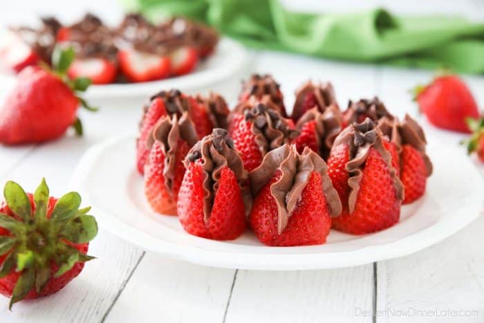 Plate of strawberries filled with no bake chocolate cheesecake filling and topped with mini chocolate chips.