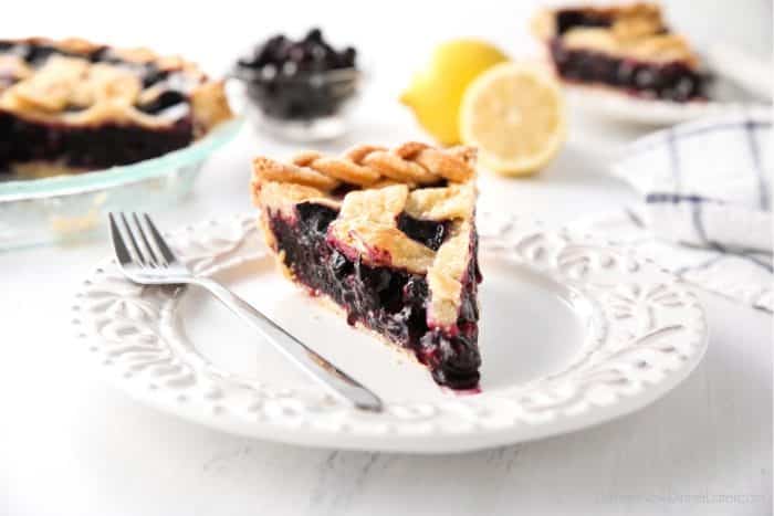 Slice of easy homemade blueberry pie on a plate with a fork.