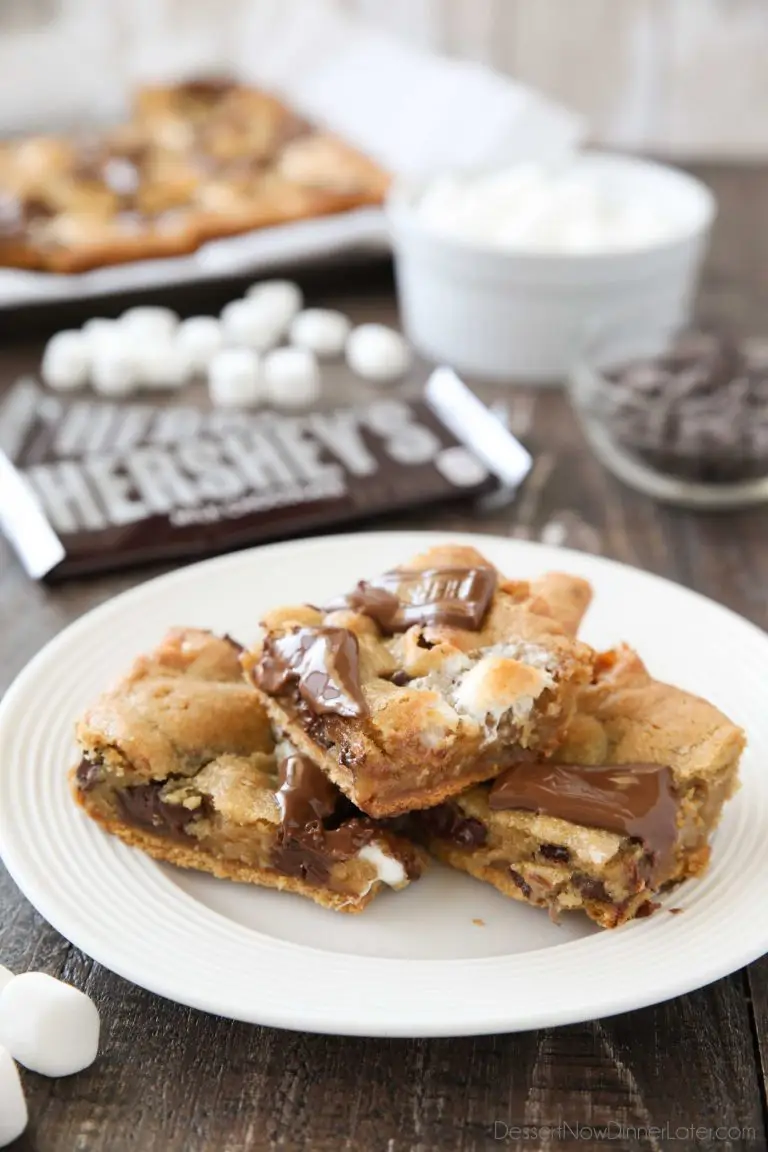 S'mores Cookie Bars are layered with graham crackers, cookie dough with marshmallows, and topped with chocolate bar pieces. It's an ooey gooey melty chocolate s'mores treat!