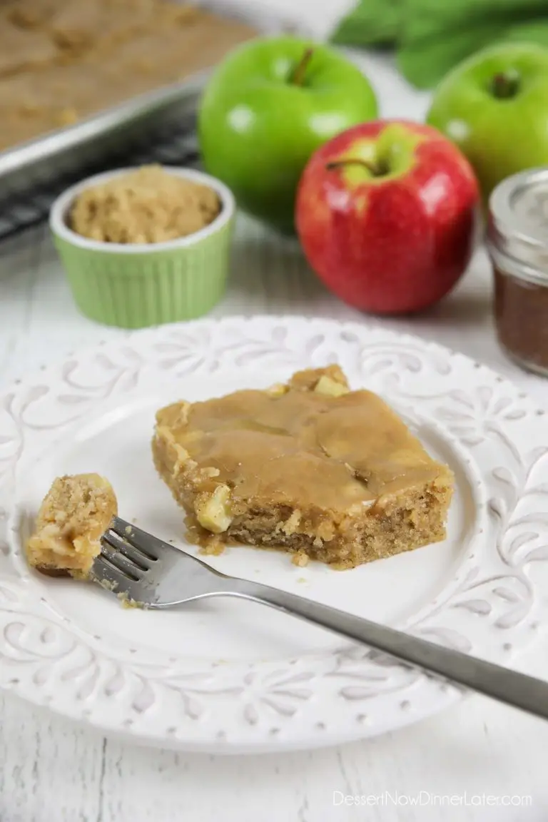 Apple sheet cake made with fresh apples and a brown sugar glaze on top. A fork full on plate ready to eat.