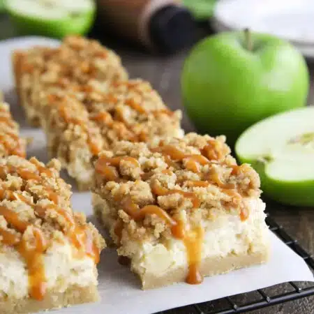 Caramel Apple Cheesecake Bars on a parchment lined wire cooling rack with caramel dripping down the sides.