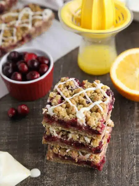 Cranberry Crumble Bars stacked with glaze drizzled on top.