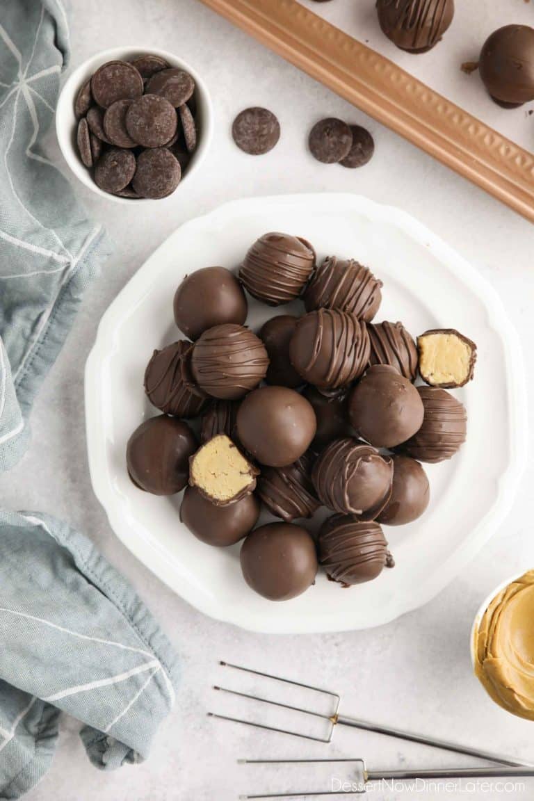 Easy Peanut Butter Balls stacked on a plate. Some drizzled, some plain, and two halves showing the peanut butter interior.