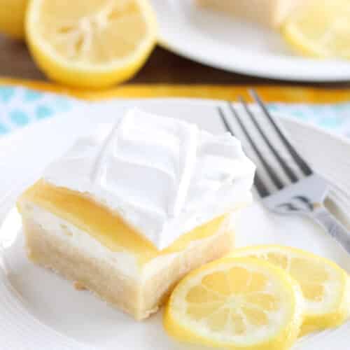 Lemon curd dessert square on plate made with a shortbread crust, sweetened cream cheese, lemon curd, and whipped cream.