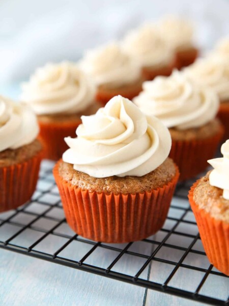 Cooling rack with cream cheese frosted carrot cake cupcakes.