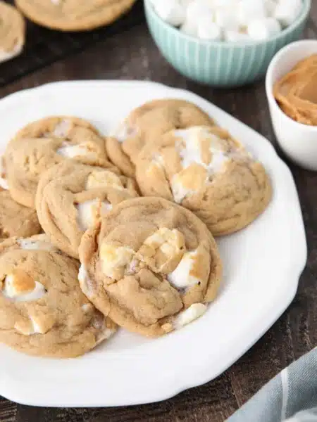 Fluffernutter cookies on a plate with bowls of mini marshmallows and peanut butter in the background.