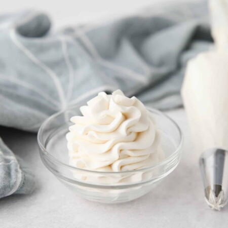 Whipped Cream Cheese Frosting piped high into a clear glass bowl.