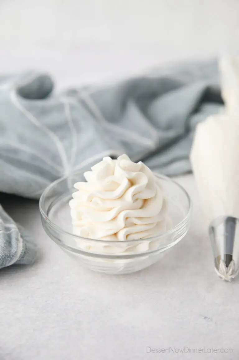 Whipped Cream Cheese Frosting piped high into a clear glass bowl.