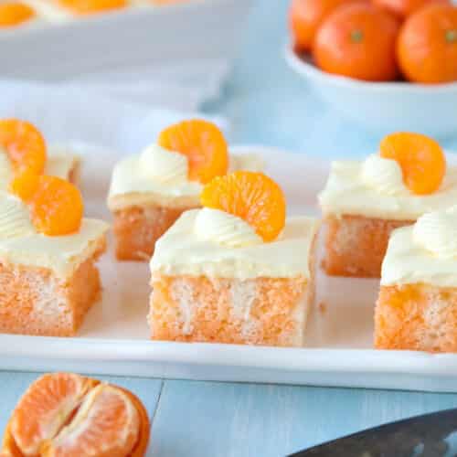 Slices of Orange Creamsicle Cake on a plate with mandarin orange slices on top.