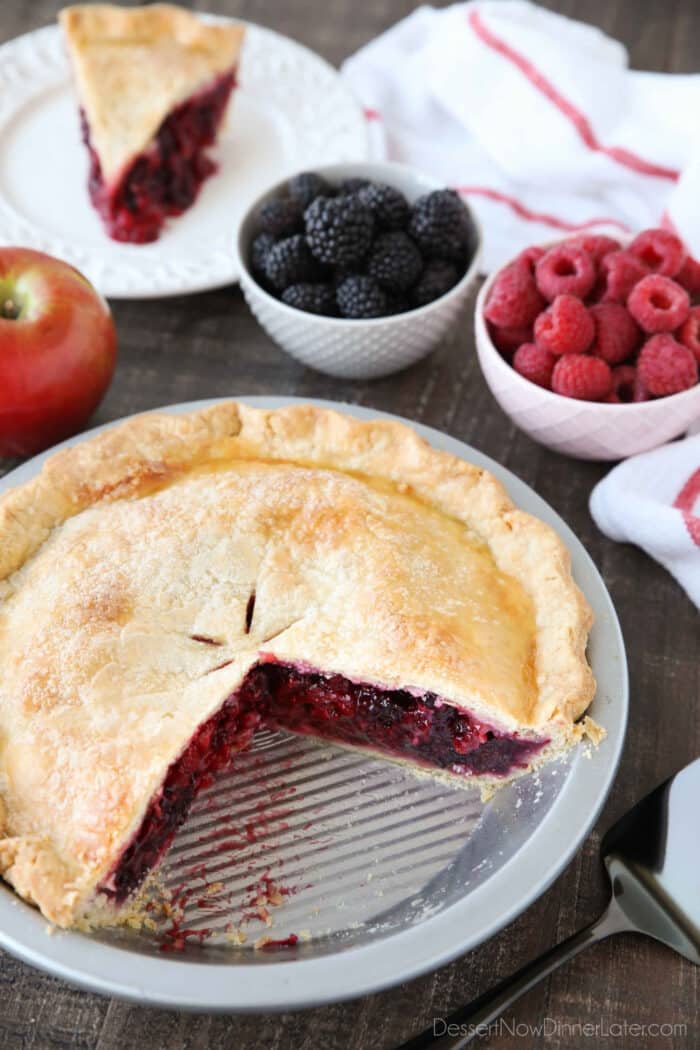 Razzleberry Pie in the pan with a slice on a plate in the background.