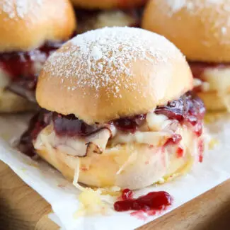 Close up of ham, turkey, and Swiss cheese mini sandwiches with raspberry preserves.