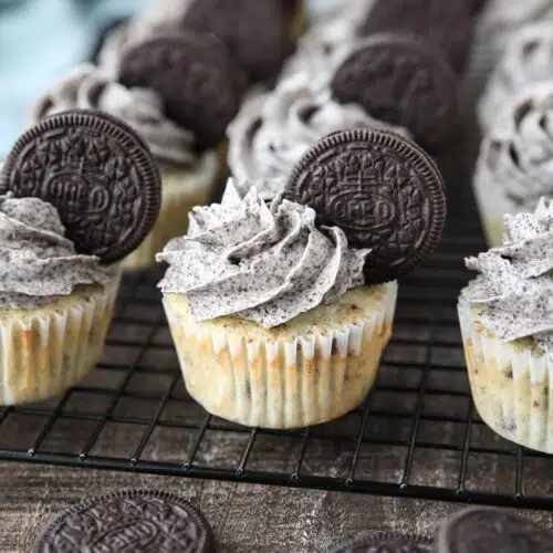 Closeup of vanilla cupcakes with Oreos inside and Oreo frosting on top with an Oreo cookie garnish.