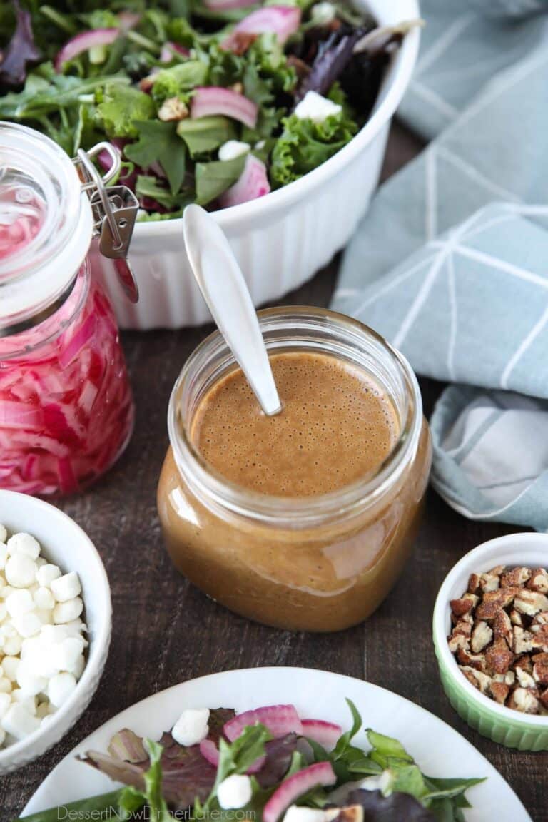 Focus on a glass mason jar of thick and creamy balsamic dressing with a spoon inside.