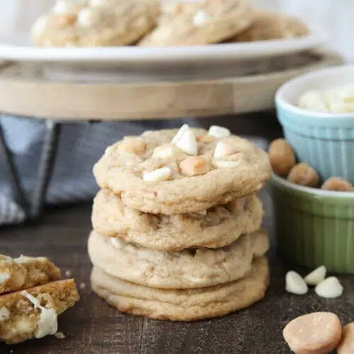 Stacked White Chocolate Macadamia Nut Cookies with extra nuts and white chocolate chips on the side.