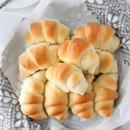 Fluffy homemade crescent rolls in a bread basket.