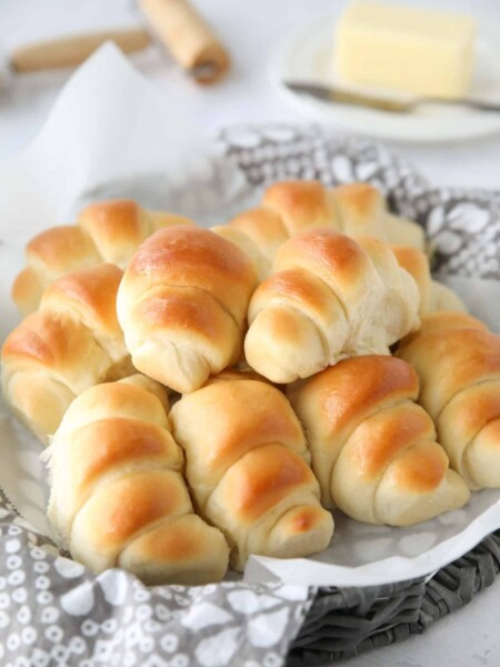 Side view of a basket full of crescent shaped dinner rolls.