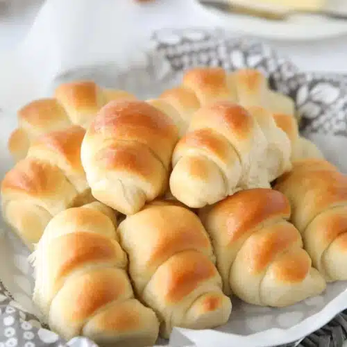 Side view of a basket full of crescent shaped dinner rolls.