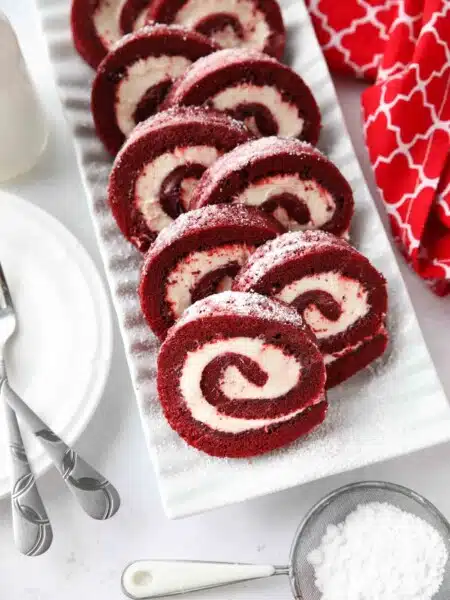 Rectangular platter with swirls of red velvet cake roll filled with cream cheese frosting.