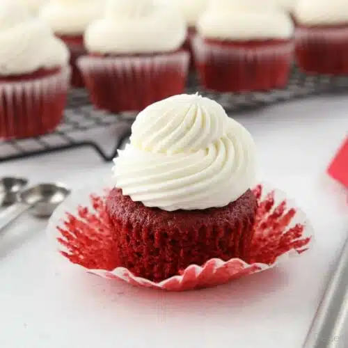 A red velvet cupcake with the wrapper pulled down to show the fluffy moist texture.