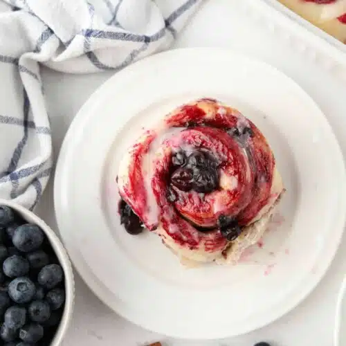 Top view of single blueberry cinnamon roll on a plate.