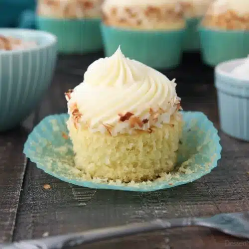 Close-up side view of a coconut cupcake with the paper wrapper pulled down.