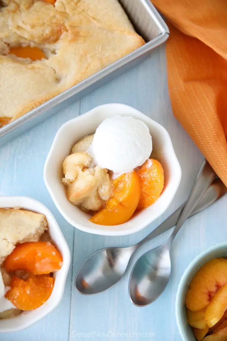 Peach Cobbler with cake batter crust on top and a scoop of vanilla ice cream.