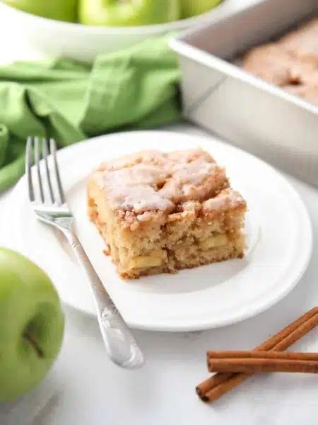 Square piece of glazed apple fritter cake on a plate.