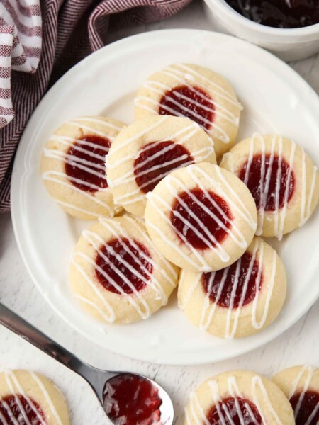 Top view of plate of raspberry thumbprint cookies with icing drizzle.