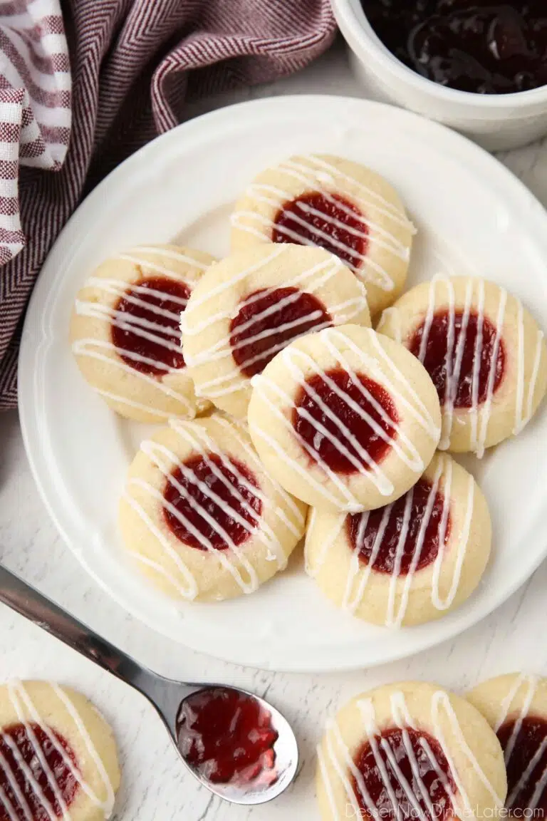 Top view of plate of raspberry thumbprint cookies with icing drizzle.