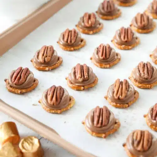 Rolo Pretzel Turtles on a baking sheet.