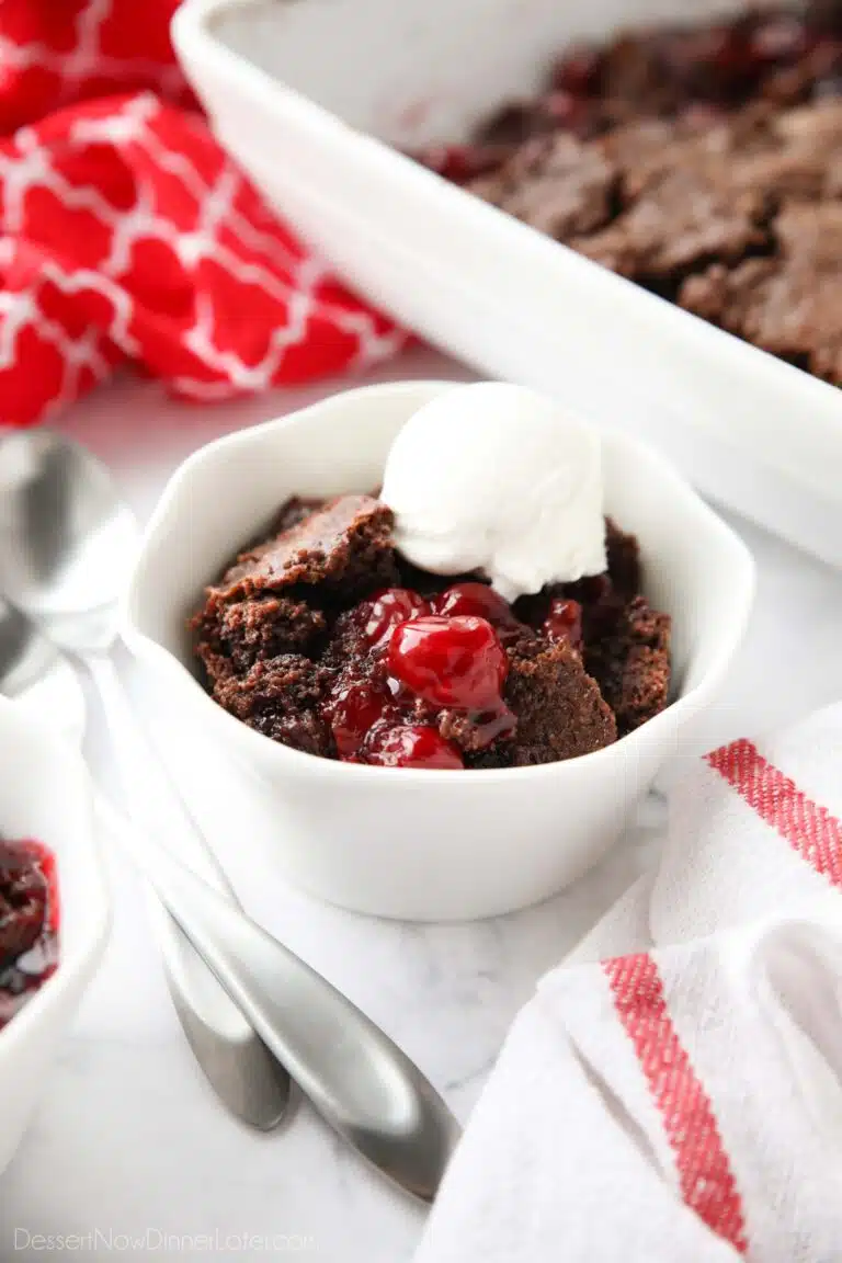 Chocolate cherry dump cake in a small bowl topped with vanilla ice cream.