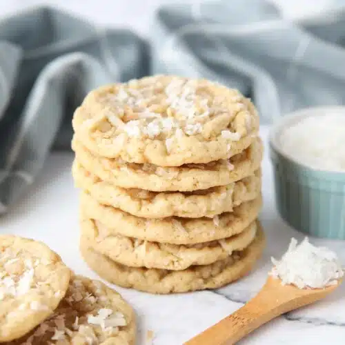 A stack of soft and chewy coconut cookies with extra shredded coconut on top.