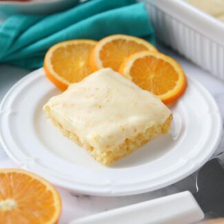 Orange Brownies on a plate with slices of oranges.