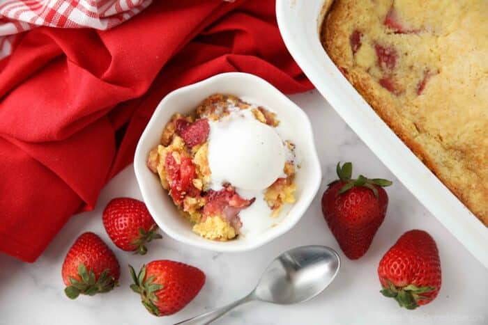 Strawberry dump cake made with fresh strawberries in a bowl with ice cream on top.