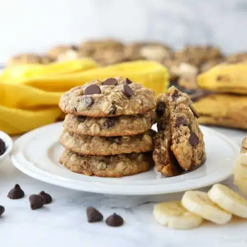 Stack of banana oatmeal chocolate chip cookies on a plate with one cookie broken in half.