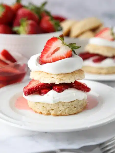 Stack of strawberry shortcake made with biscuits, whipped cream, and strawberries.