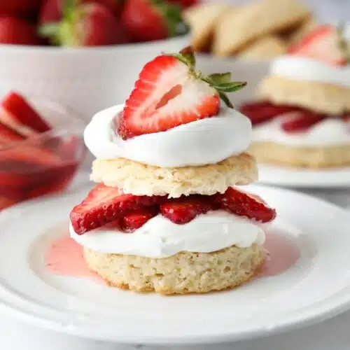 Stack of strawberry shortcake made with biscuits, whipped cream, and strawberries.