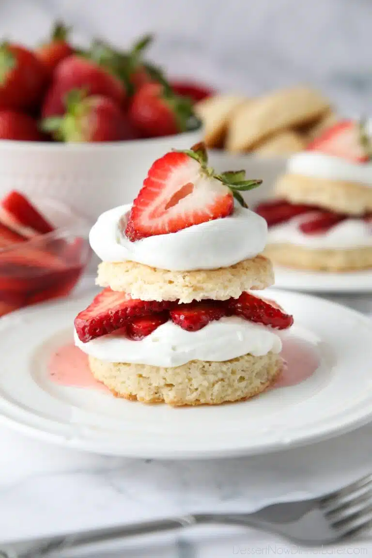 Stack of strawberry shortcake made with biscuits, whipped cream, and strawberries.