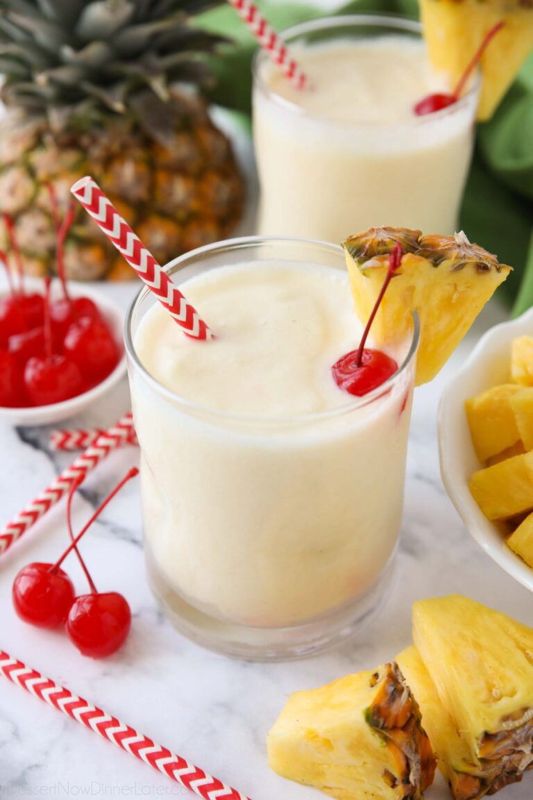 Virgin pina colada in a glass cup with a wedge of pineapple, a maraschino cherry, and a straw.