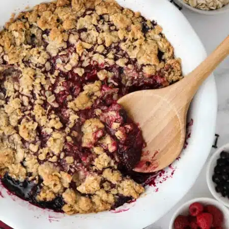 Spooning berry crisp (aka berry crumble) out of dish.