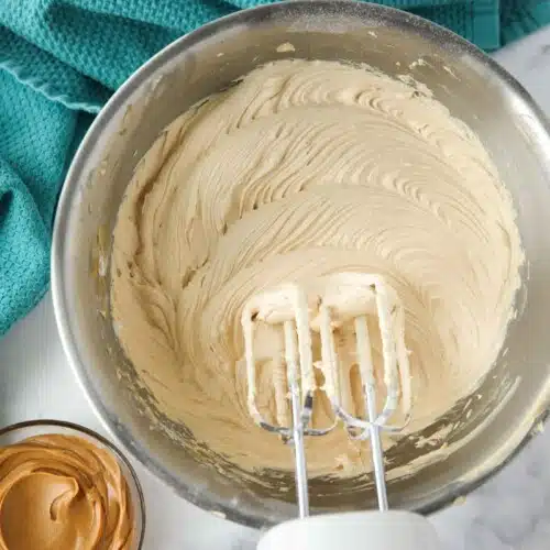 Bowl of peanut butter frosting made with an electric and mixer.